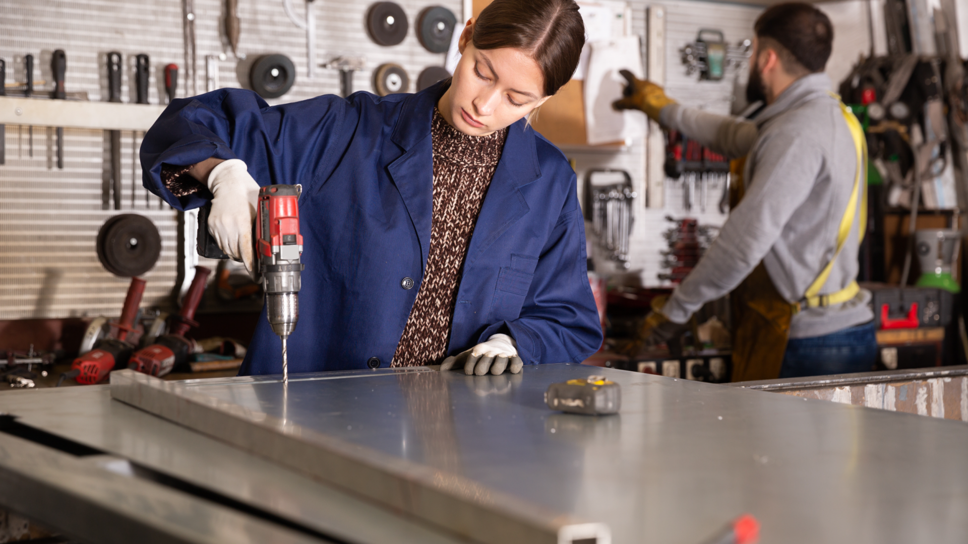mujer usando un taladro trabajando en un taller de acero